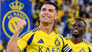 كريستيانو رونالدو يحتفل بقميص نادي النصر السعودي بعد تسجيل هدف، رافعاً قبضته وسط أجواء حماسية، مع ظهور شعار النصر في خلفية الصورة، في مشهد يعكس فرحة النجم البرتغالي وأدائه مع الفريق.