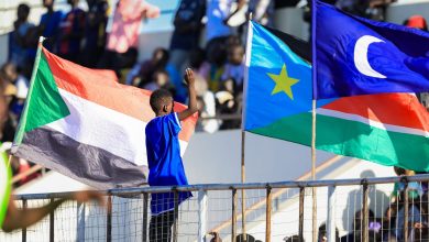 مشهد من مدرجات مباراة الهلال السوداني وجاموس الجنوب سوداني في جوبا، حيث يرفع طفل أعلام السودان وجنوب السودان والهلال في أجواء جماهيرية مميزة.