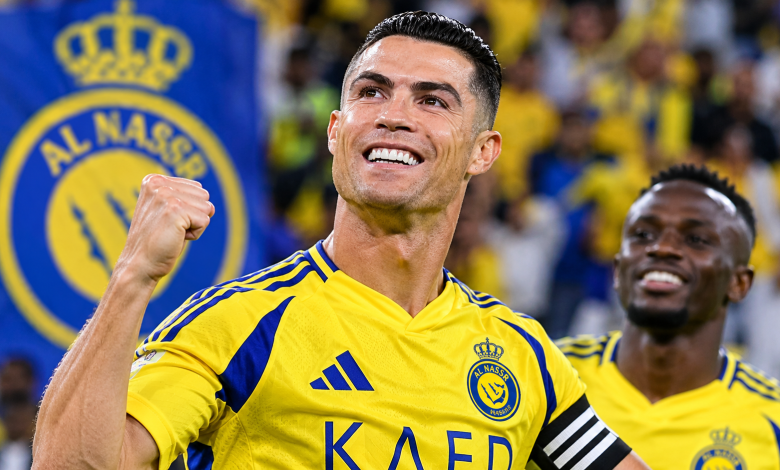كريستيانو رونالدو يحتفل بقميص نادي النصر السعودي بعد تسجيل هدف، رافعاً قبضته وسط أجواء حماسية، مع ظهور شعار النصر في خلفية الصورة، في مشهد يعكس فرحة النجم البرتغالي وأدائه مع الفريق.