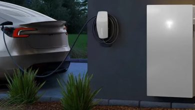 سيارة Tesla Model 3 متوقفة بجوار منزل حديث مزود بوحدات Powerwall 3 ونظام شحن، في مشهد يوضح استخدام بطارية السيارة كمصدر للطاقة الاحتياطية للمنزل.