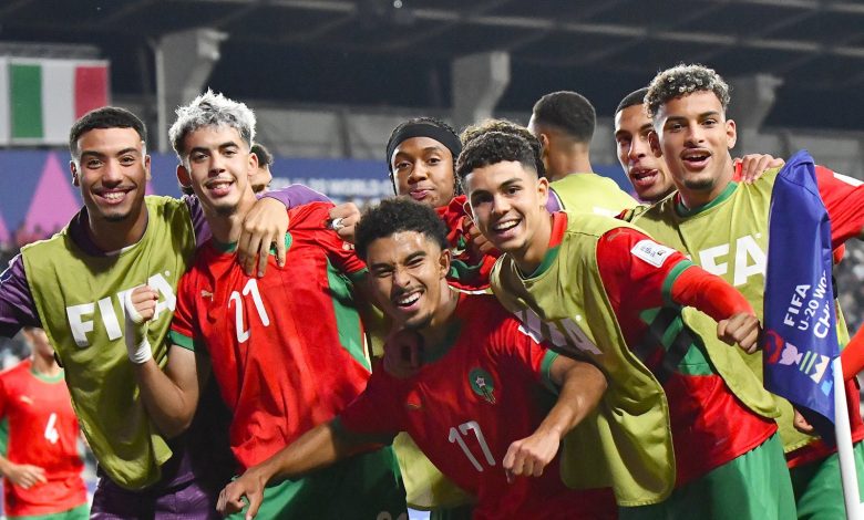 صورة جماعية لمنتخب المغرب للشباب يحتفلون بالتأهل في الملعب، واللاعبون يرفعون الأيدي فرحًا بالانتصار.