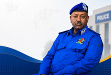 تصميم إخباري يظهر مسؤولاً شرطياً سودانياً بخلفية مخصصة لمقال حول اتهامات بفرض رسوم غير قانونية داخل قسم شرطة المهدية