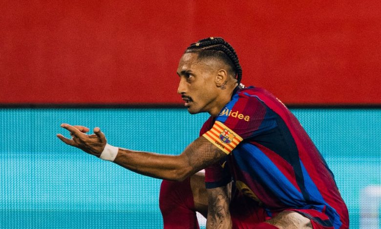 صورة احترافية للاعب نادي برشلونة رافينيا وهو يحتفل بتركيز على أرضية الملعب بعد إحرازه هدفاً، مرتديياً قميص البلوغرانا مع شارة القيادة، وذلك خلال مباراته الحاسمة ضد نادي إشبيلية في الدوري الإسباني.