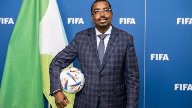 سليمان حسن وبيري رئيس الاتحاد الجيبوتي لكرة القدم خلال ظهور رسمي أمام خلفية تحمل شعار الاتحاد الدولي لكرة القدم فيفا.