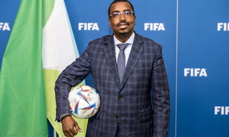 سليمان حسن وبيري رئيس الاتحاد الجيبوتي لكرة القدم خلال ظهور رسمي أمام خلفية تحمل شعار الاتحاد الدولي لكرة القدم فيفا.